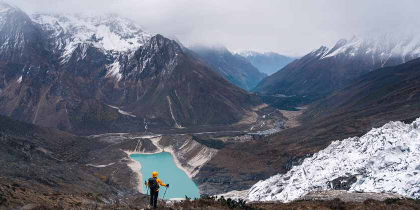 "Snow-capped peaks of Mount Manaslu towering above the trekking path, with lush green valleys and clear blue skies in the foreground."