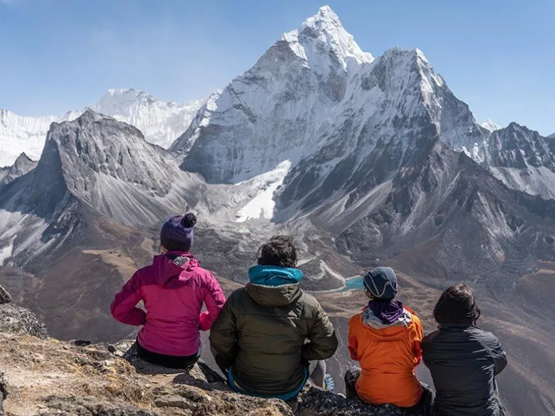 Tourists resting and acclimatizing in Dingboche village while overlooking snow-covered Himalayan peaks during the Everest Base Camp trek.