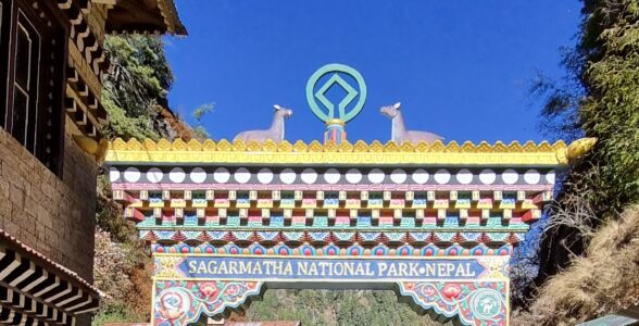 Colorful traditional entrance gate of Sagarmatha National Park in Nepal with Himalayan village and forest backdrop