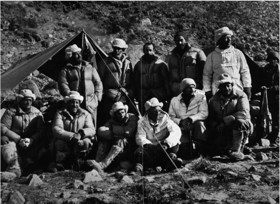 Group portrait of the 1952 Spring Ror2 Expedition team, showing Swiss mountaineers and scientists seated and standing at a high-altitude campsite, wearing cold-weather gear in a rocky mountain landscape.