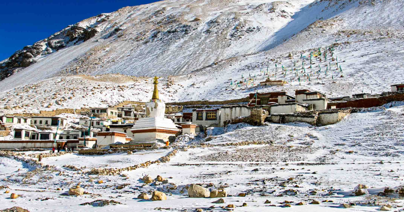 Rongbuk Monastery covered in snow during winter, set against barren Himalayan slopes near Mount Everest in Tibet.