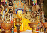Golden statue of Jowo Shakyamuni Buddha seated inside Jokhang Temple, surrounded by ornate offerings and intricate decorations.