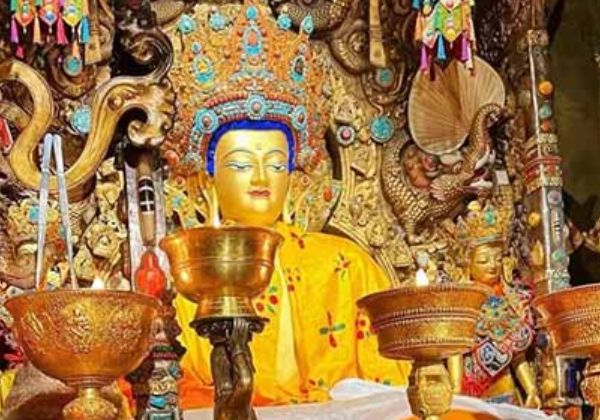 Golden statue of Jowo Shakyamuni Buddha seated inside Jokhang Temple, surrounded by ornate offerings and intricate decorations.