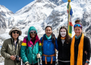 A group of five legendary female mountaineers standing together at the Everest Base Camp, with Mount Everest in the background.