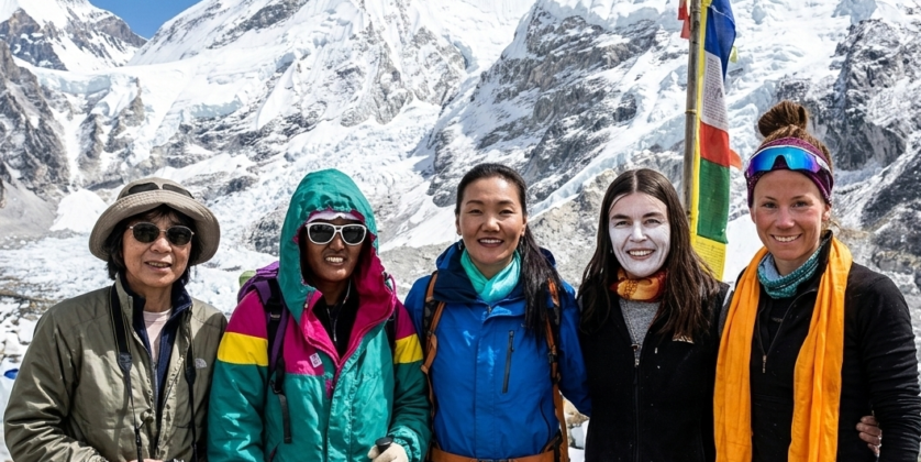 A group of five legendary female mountaineers standing together at the Everest Base Camp, with Mount Everest in the background.