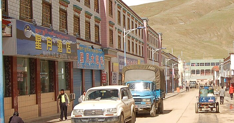 Commercial street in Saga with shops, vehicles, and pedestrians along the road