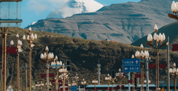 Road in Darchen leading toward Mount Kailash with streetlights and distant snow peak