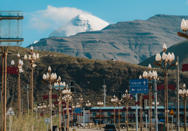 Road in Darchen leading toward Mount Kailash with streetlights and distant snow peak