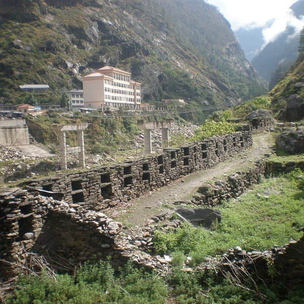 Historical stone fortifications in Kerung (Kyirong), Tibet, with mountainous terrain and modern buildings in the background.