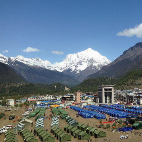 Bird’s-eye view of Keyrung showing a mountain town with rows of tents and buildings set against snow-capped Himalayan peaks.