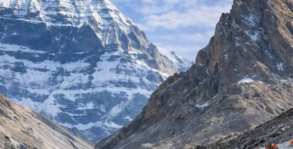 Mount Kailash with Nandi Parvat in front, framed by colorful prayer flags along the rocky pilgrimage trail.