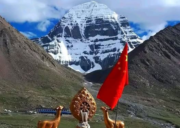 Snow-covered south face of Mount Kailash viewed from DiraPuk Monastery, with a prayer shrine and flags in the foreground against a clear Himalayan sky.