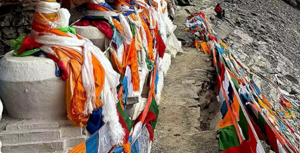 Prayer flags and chortens lining the narrow Saptarishi Cave path near Mount Kailash during the sacred parikrama route.
