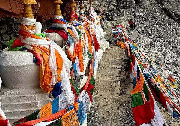 Prayer flags and chortens lining the narrow Saptarishi Cave path near Mount Kailash during the sacred parikrama route.