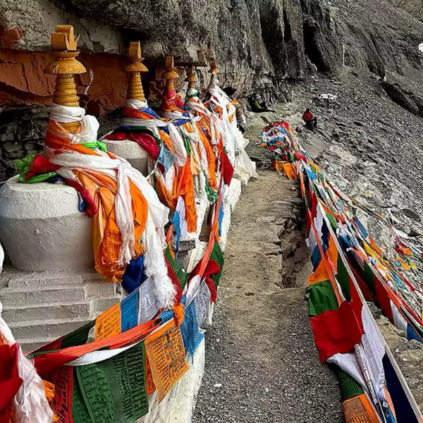 Prayer flags and chortens lining the narrow Saptarishi Cave path near Mount Kailash during the sacred parikrama route.
