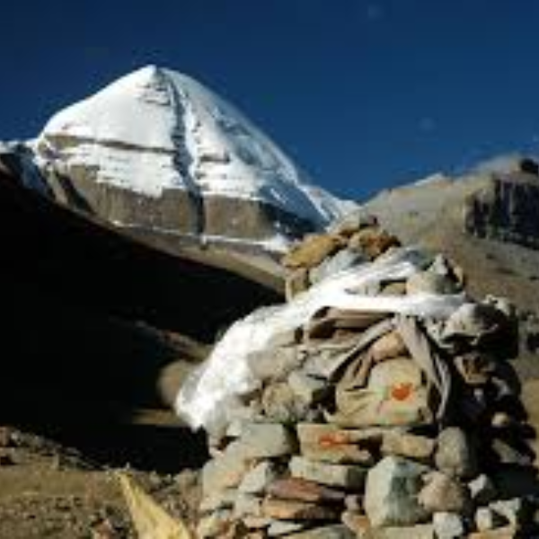 Rock cairn marking the trekking route to Ashtapad with a snow-covered peak in the background in the Kailash region.