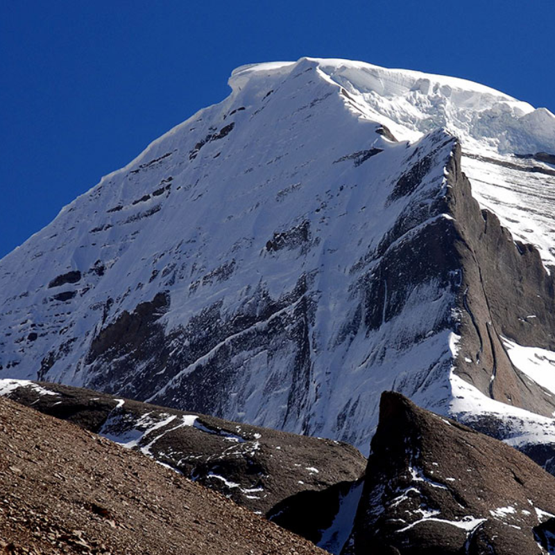 West face of Mount Kailash with steep snow-covered slopes under a clear blue sky