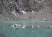 Close view of turquoise Gauri Kund lake surrounded by rocky cliffs near Dolma La Pass.