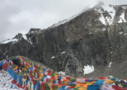 Prayer flags at Dolma La Pass surrounded by snowy rocky mountains