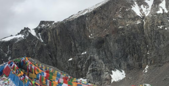 Prayer flags at Dolma La Pass surrounded by snowy rocky mountains
