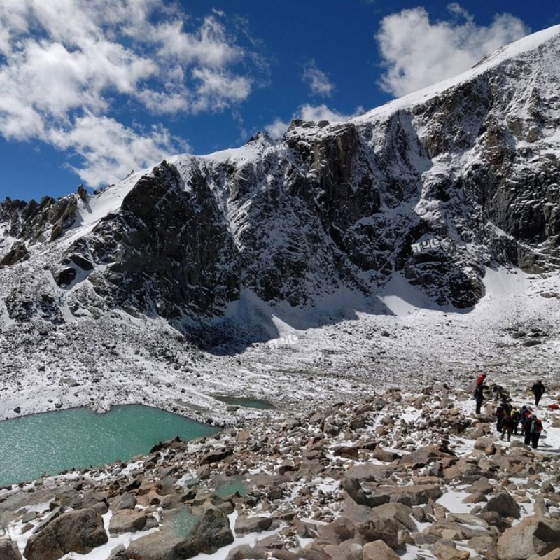 Pilgrims trekking along the snowy Kora path near Dolma La Pass and turquoise lakes in Tibet.