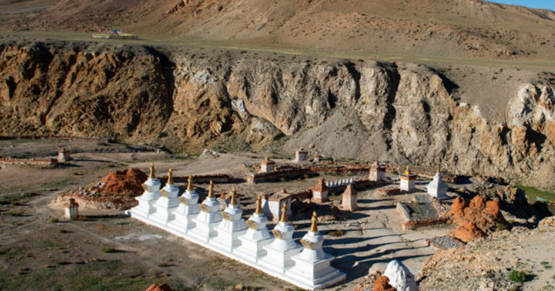 Tirthapuri Gompa and white stupas surrounded by rocky hills near Mount Kailash in Tibet.