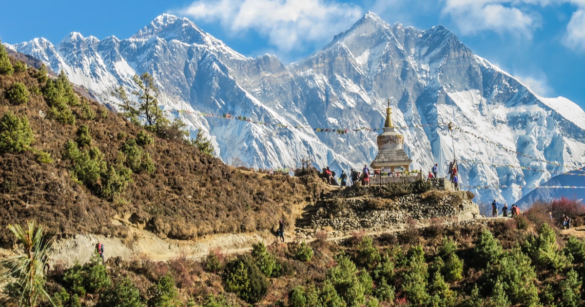 Trekkers hiking toward Everest Base Camp with snow-capped Himalayan peaks in the background.