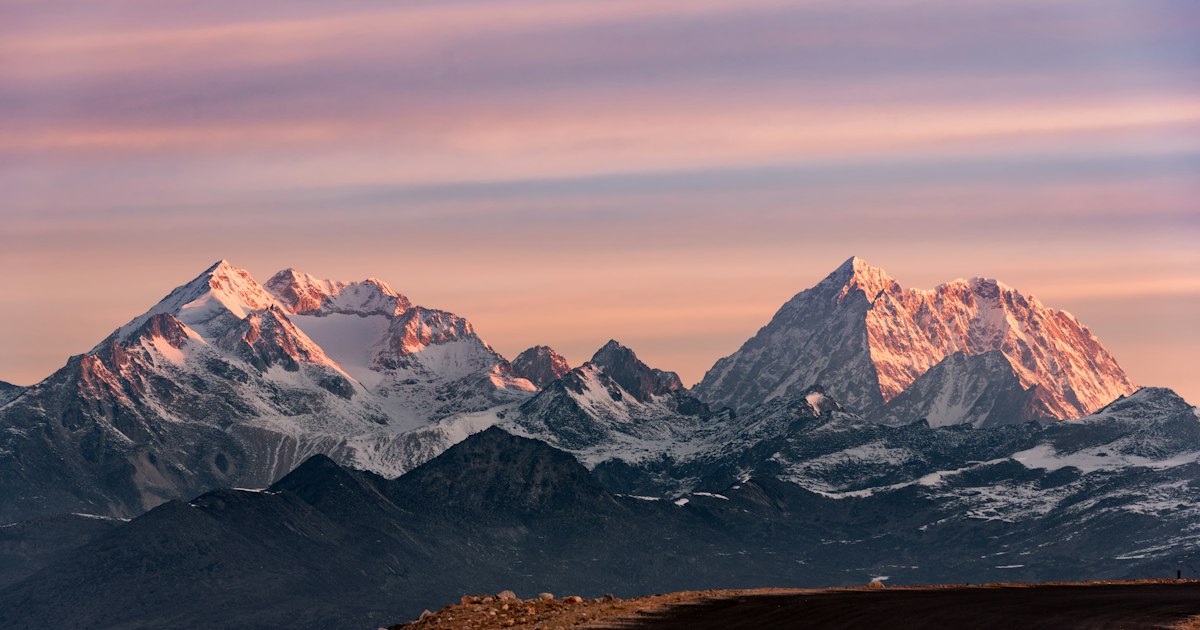 Snow-capped Annapurna mountain range rising above clouds against a clear blue Himalayan sky in Nepal