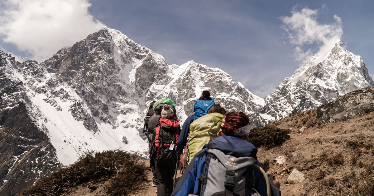 Trekkers on a high-altitude trail below snow-capped Himalayan peaks in Nepal