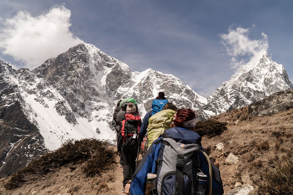 Trekkers hiking a Himalayan trail with snow-capped peaks in Nepal