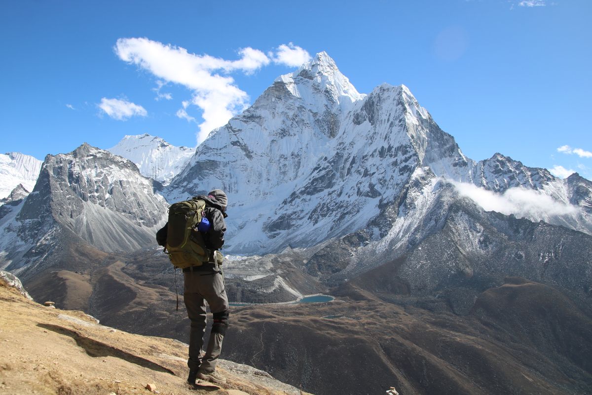 Trekker with a backpack hiking through the Himalayan mountains on the trail to Everest Base Camp in Nepal.